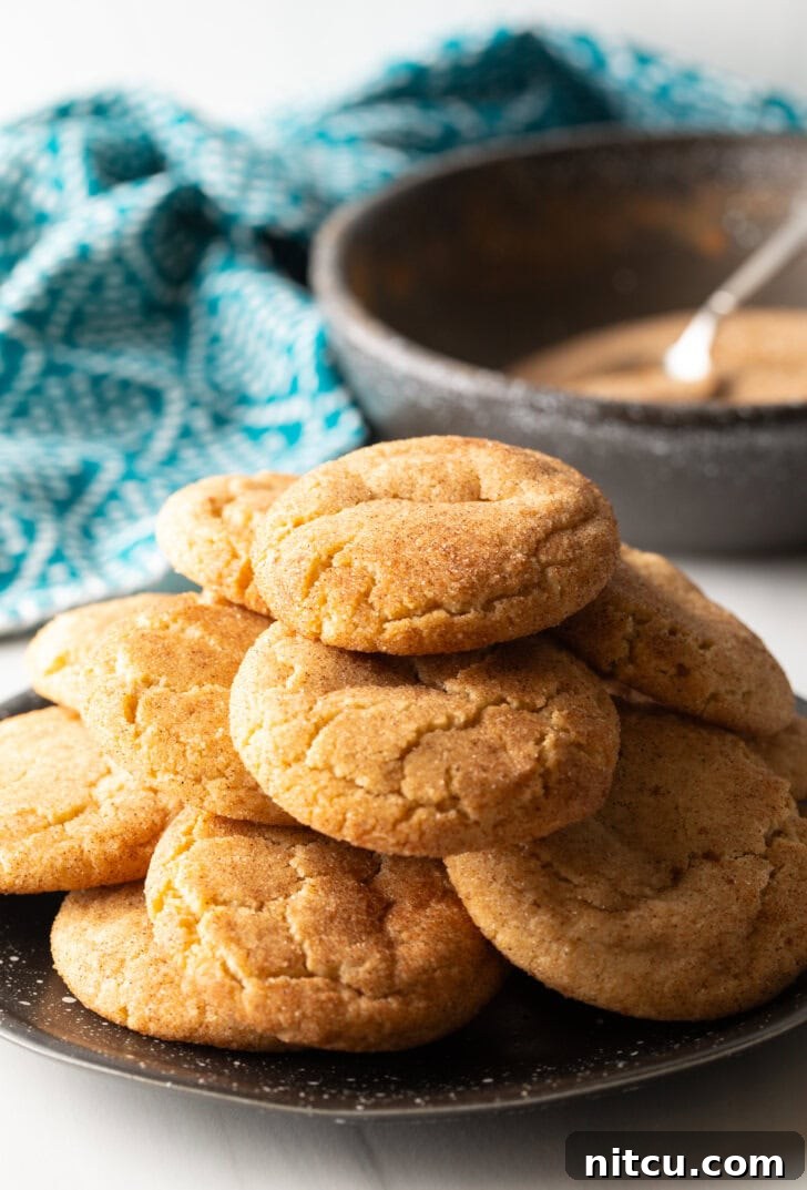 A festive plate showcasing a dozen biscochitos, neatly stacked and glistening with cinnamon sugar.