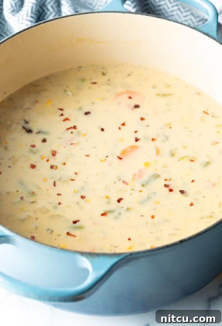 Large blue pot of creamy soup with veggies.