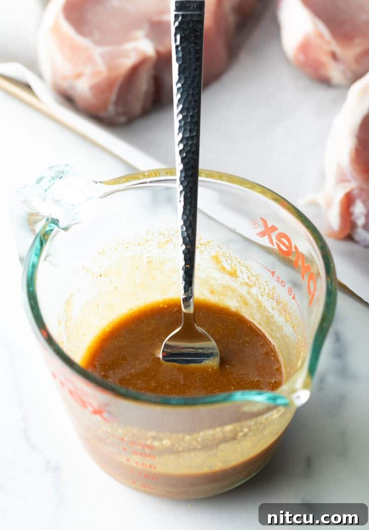 The perfectly emulsified brown soy and Dijon glaze ingredients resting in a glass measuring cup with a fork, exhibiting a smooth, inviting consistency ready for application.
