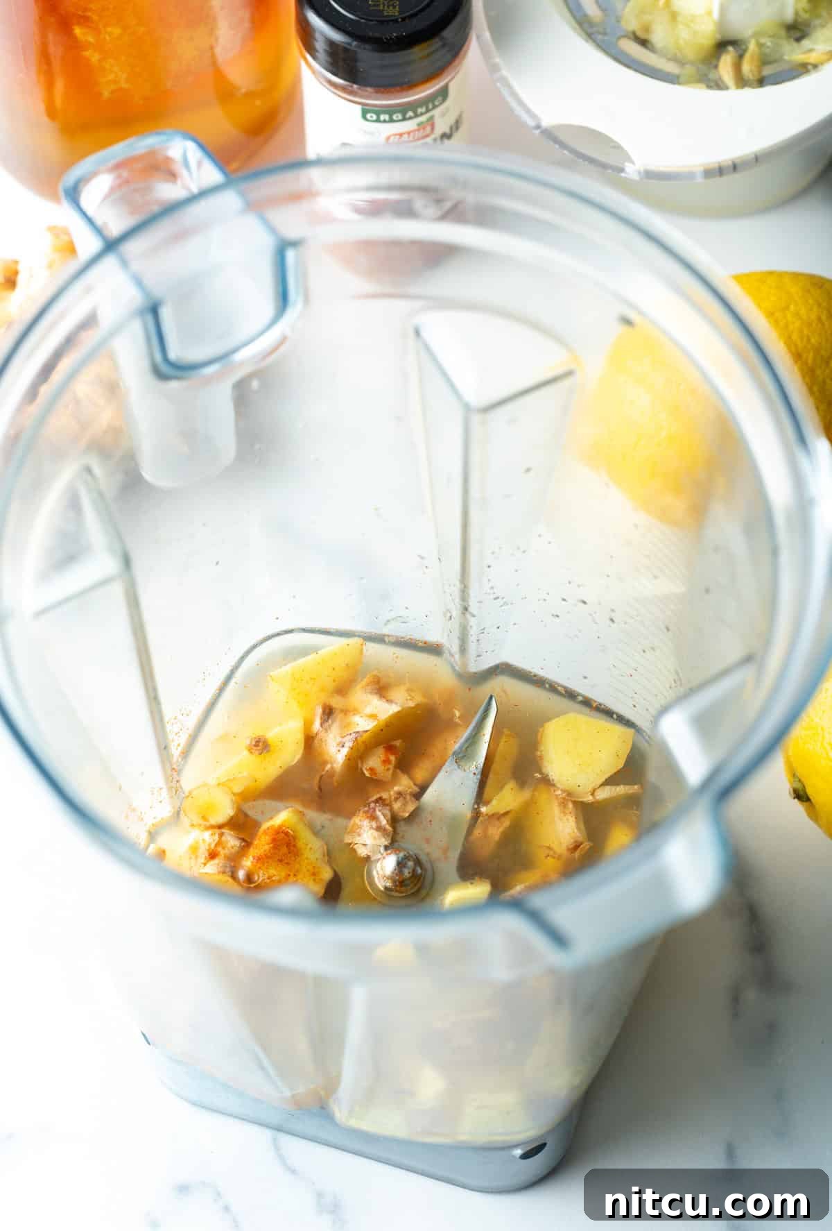 Garlic, lemon, turmeric, in a food processor, ready to be blended for the ginger shot.