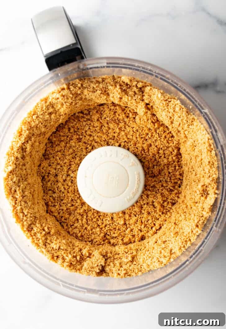 Close-up of peanuts starting to blend into crumbs in a food processor.