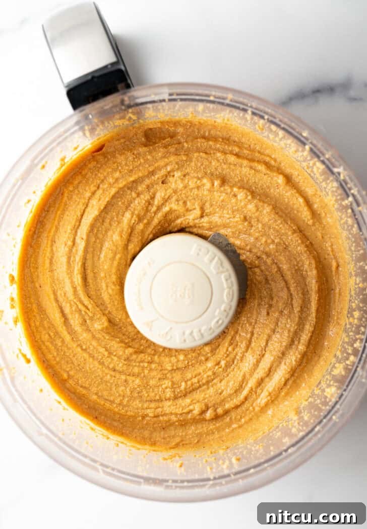 Peanuts continuing to blend, becoming slightly creamy with small chunky pieces still visible.
