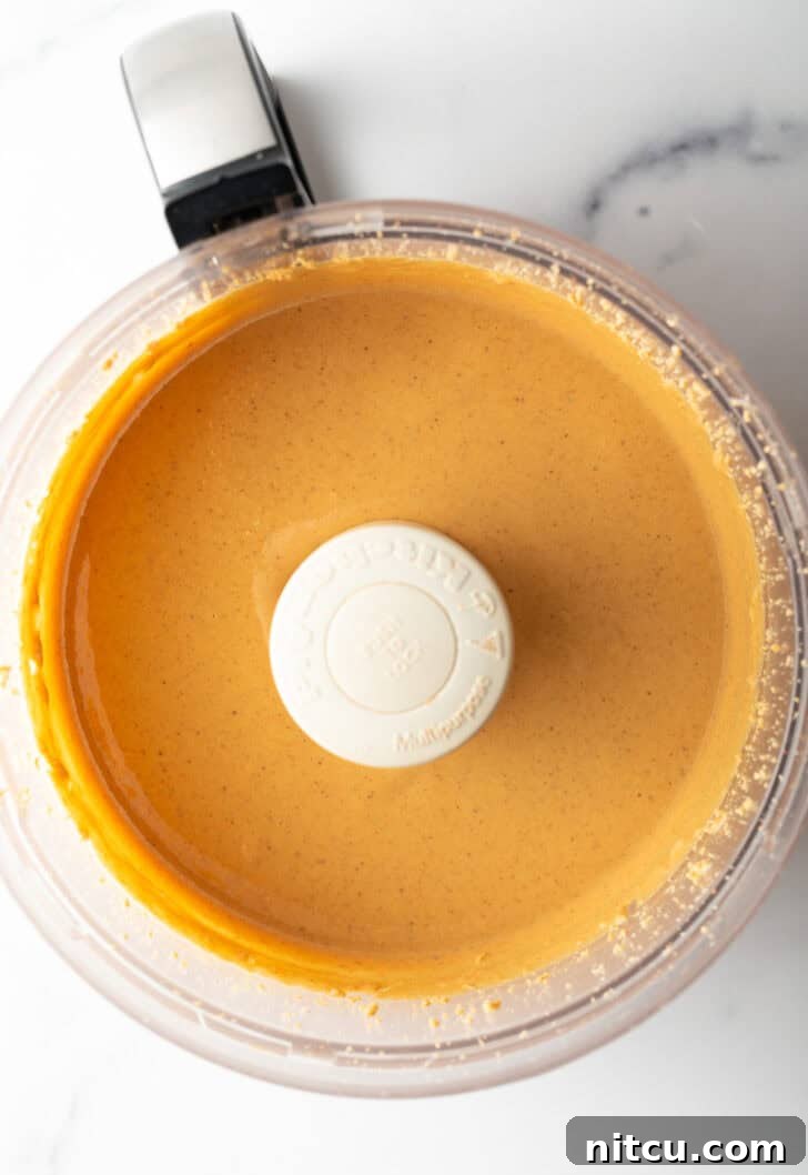 Smooth, glossy peanut butter swirling in the food processor, indicating it's nearly ready.