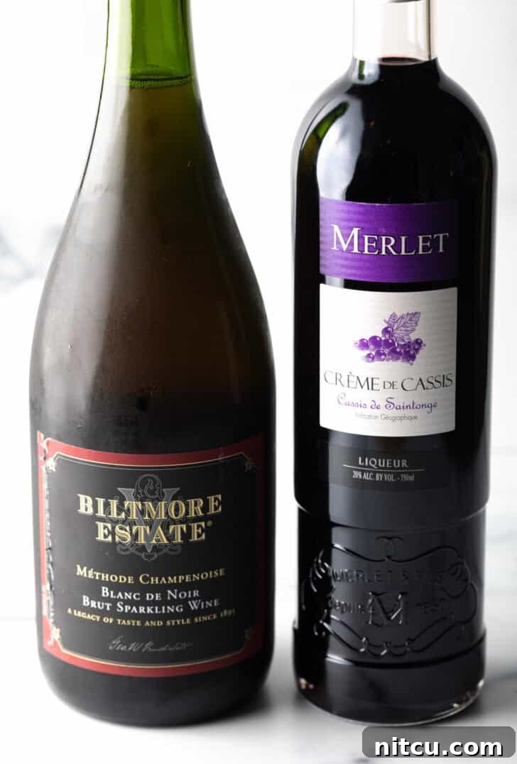 A pristine bottle of champagne stands alongside a bottle of rich crème de cassis.