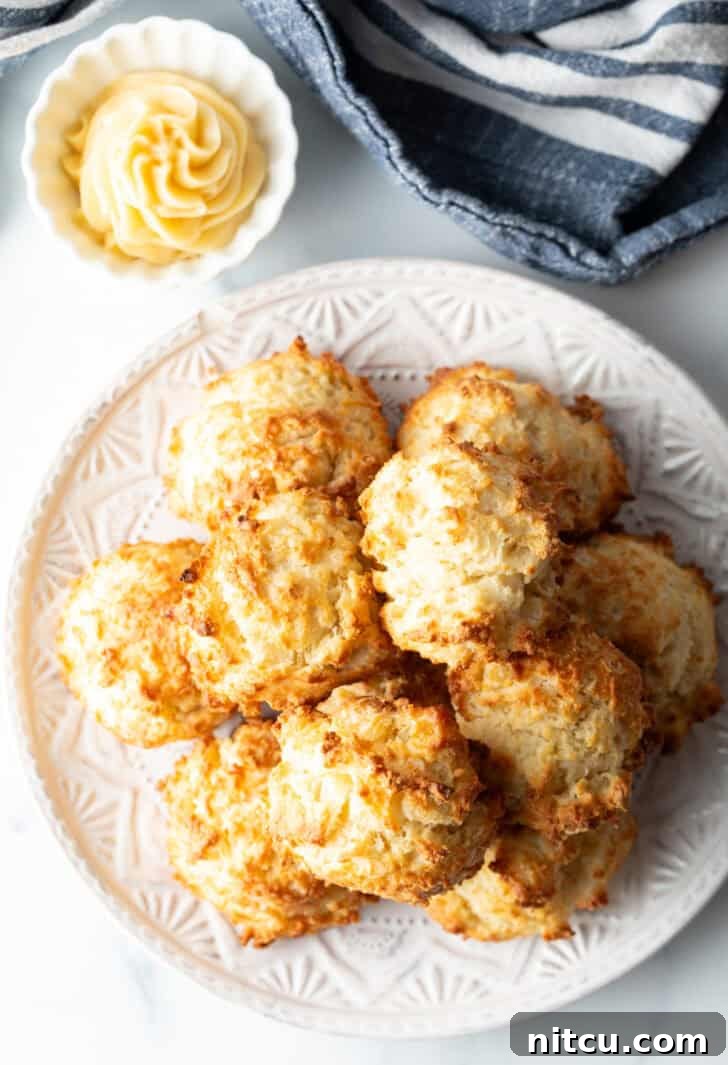 Top down view white plate with two-layer high stack of several homemade buttermilk biscuits.