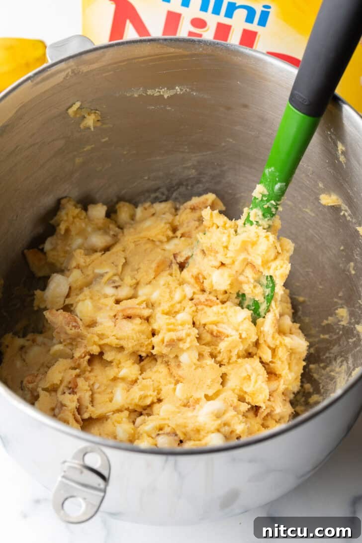Mixed cookie dough with bananas, white chocolate chips, and crushed Nilla wafers, ready for scooping.