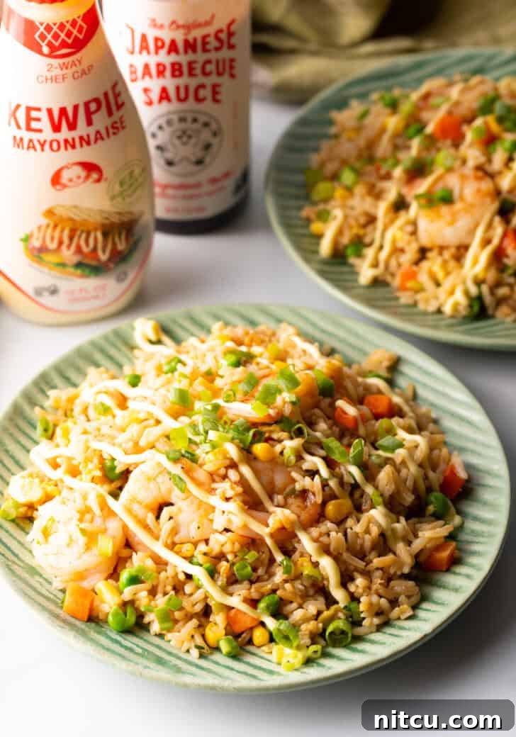 Vibrant green plate generously piled with shrimp fried rice, adorned with a tempting zig-zag drizzle of creamy yum yum sauce.