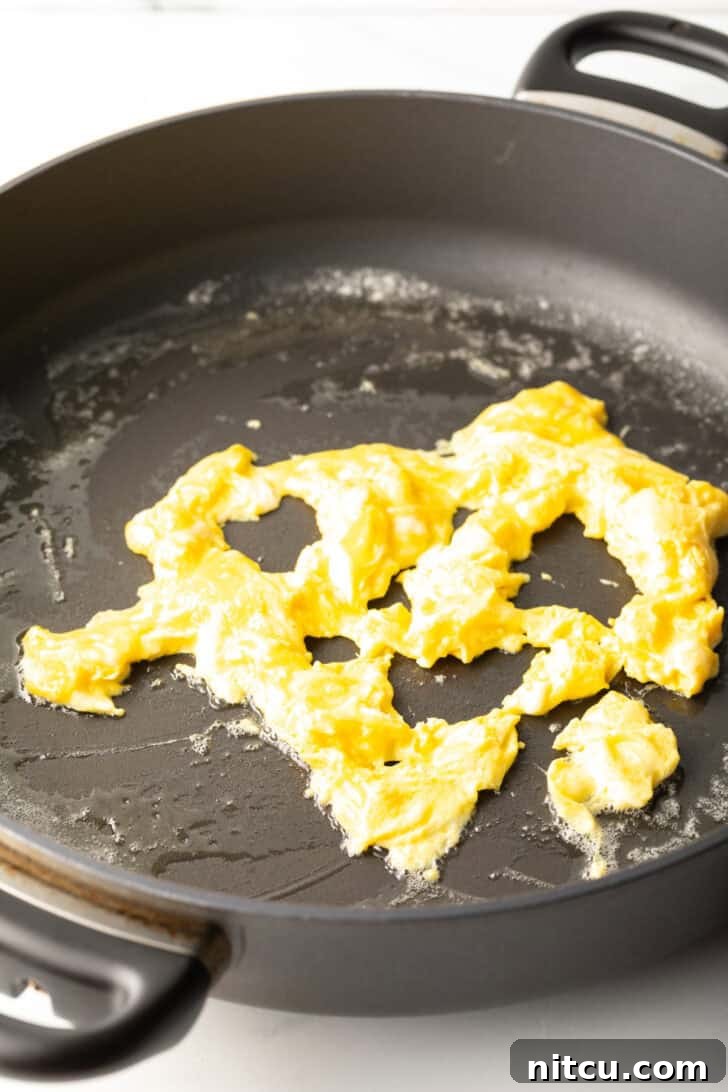 Expertly scrambling eggs in a hot skillet, creating fluffy, golden curds.