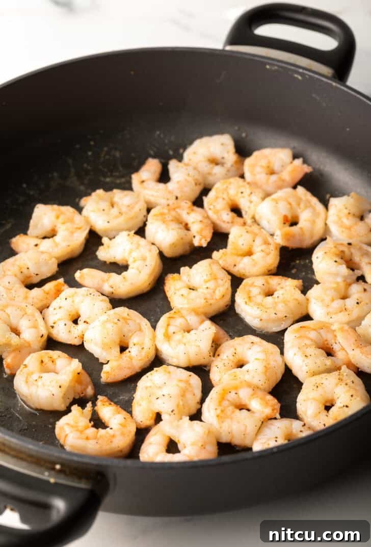 Fresh, raw shrimp being cooked to perfection in a sizzling skillet.