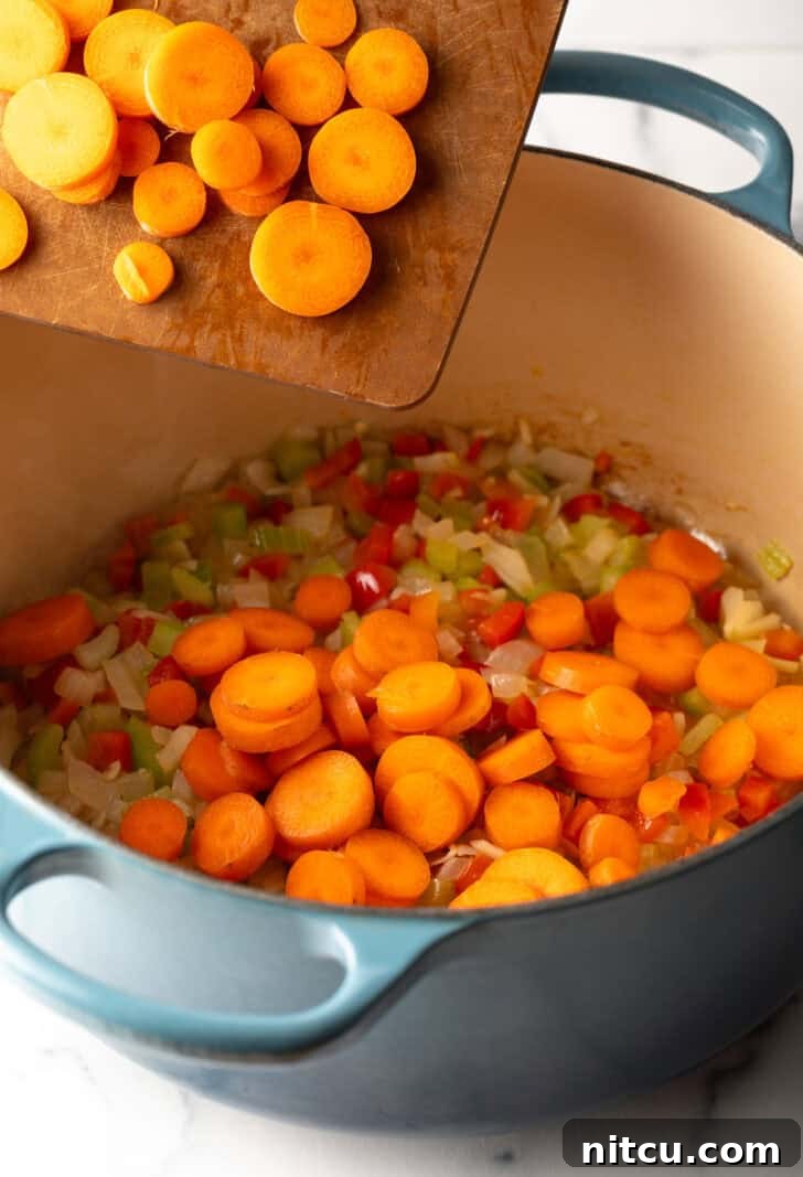 A close-up shot of raw green lentils in a measuring cup, showcasing their distinct color and texture, poised to be added to a hearty soup.
