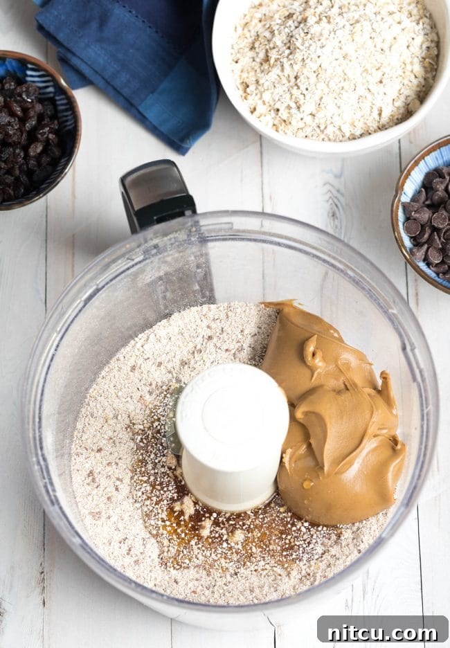 Adding creamy peanut butter to a food processor, blending it with other ingredients to form a cohesive dough.