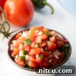 A white bowl of fresh pico de gallo with chopped tomatoes, onion, jalapeno, and cilantro.