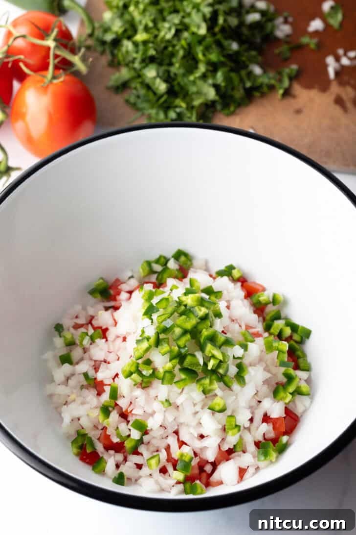 Chopped jalapenos and onion added to the bowl of chopped tomatoes.