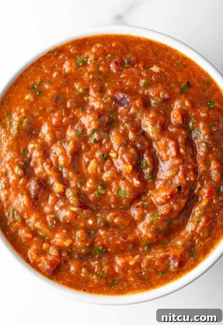 Top down view of a white bowl of red roasted tomato salsa.
