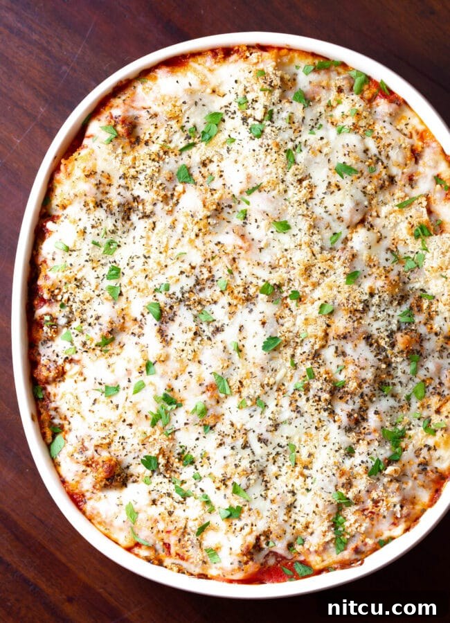 Overhead shot of a baked cream cheese lasagna in a pan, bubbling and golden brown, ready for serving.