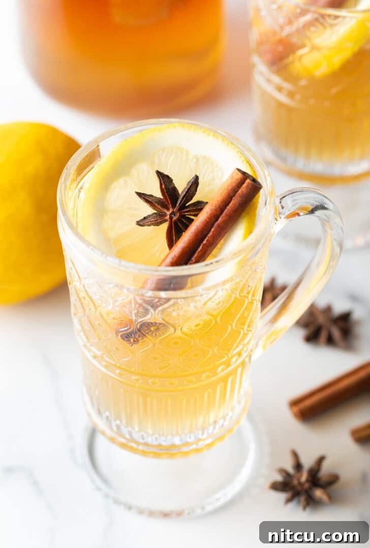 Glass handled mug with hot toddy, garnished with star anise and a cinnamon stick.