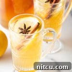 2 glass handled mugs with hot toddy, garnished with star anise and a cinnamon stick.
