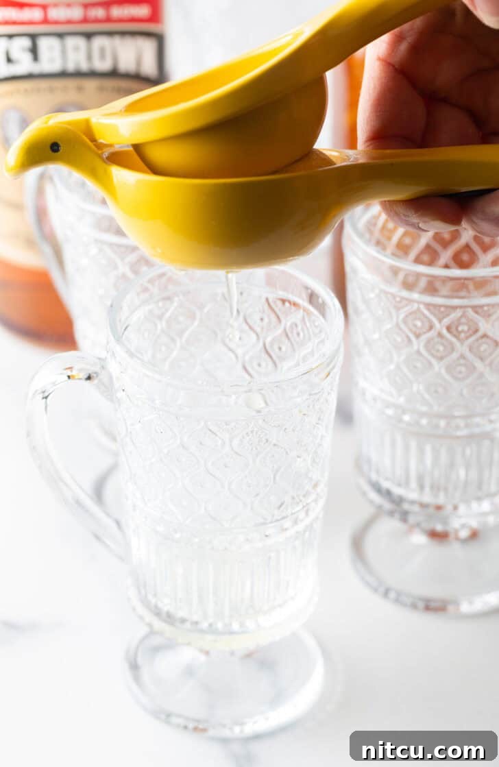 Use a yellow juicer to juice a lemon over a clear mug with handle.
