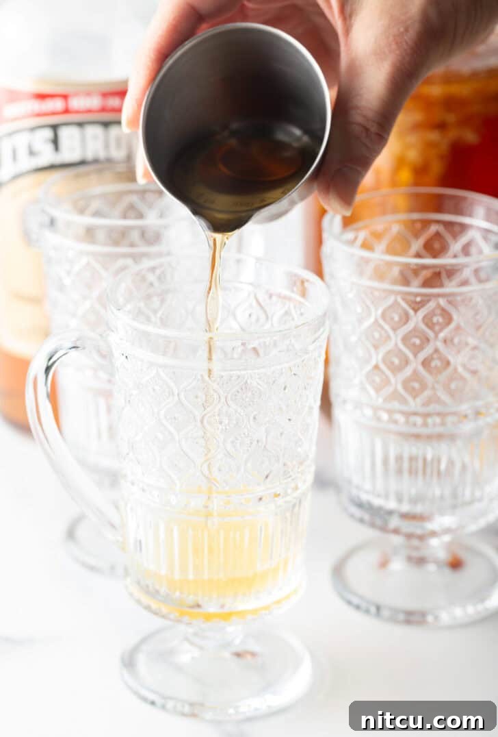 Add alcohol from a metal jig into a clear glass with a handle.