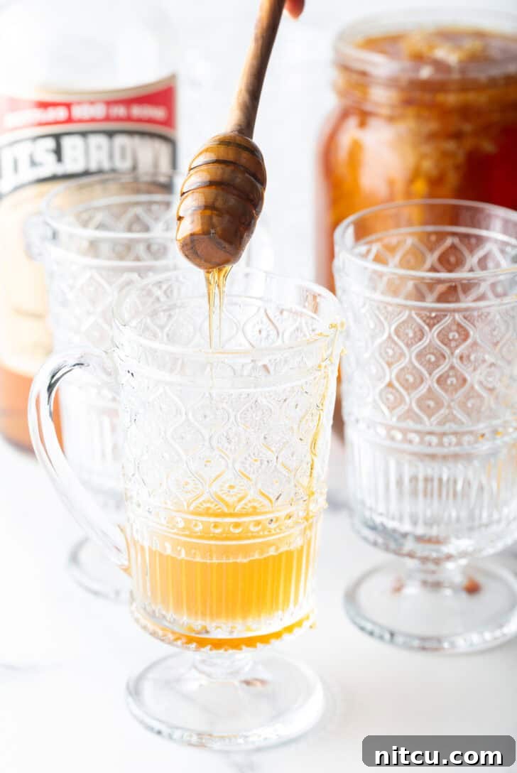 Adding honey to a clear handled mug.