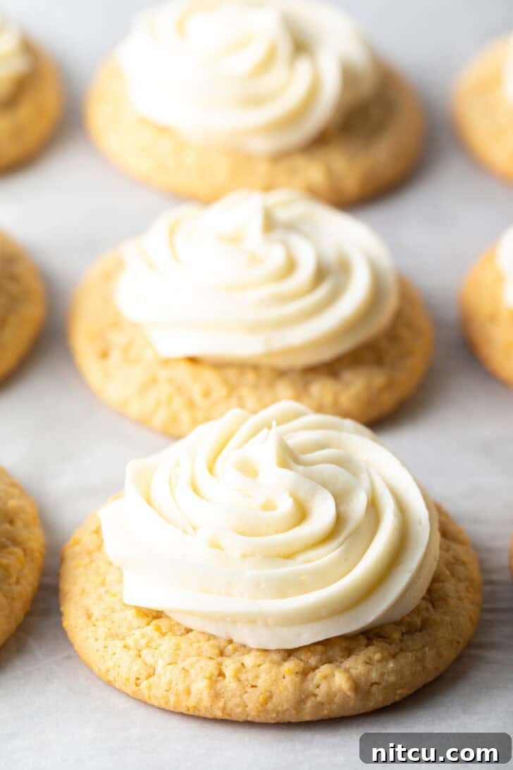 Several honey butter cornbread cookies on a white background, each topped with piped frosting.