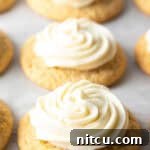 Several honey butter cornbread cookies on a white background, each topped with piped frosting.
