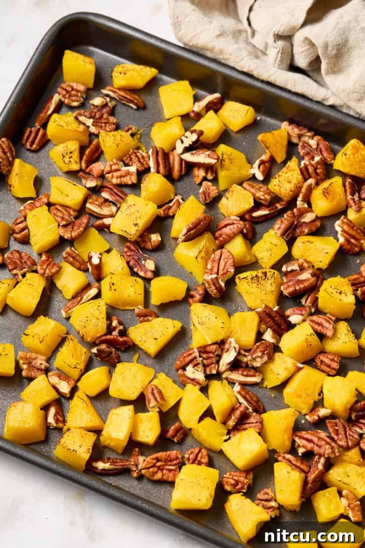 Roasted acorn squash and pecans on a baking sheet, a perfect fall combination.