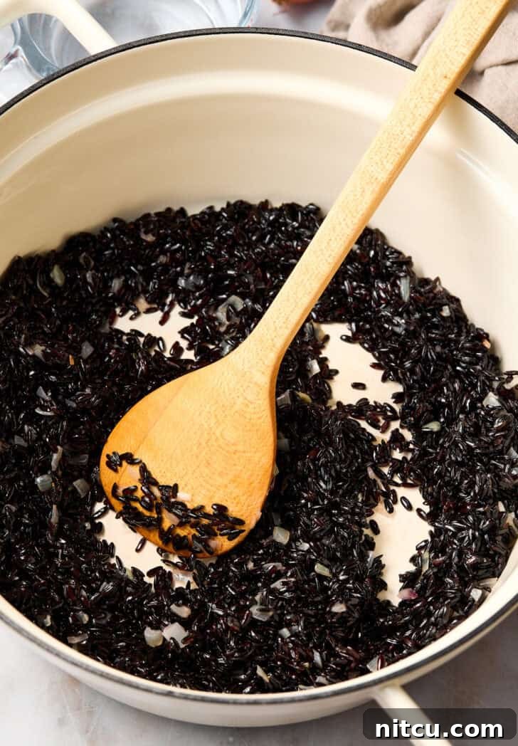 Black rice cooking in a pot on the stovetop, covered.