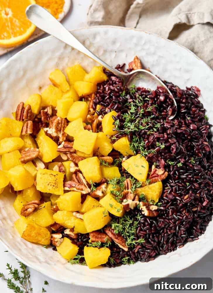 Mixing roasted acorn squash and pecans with cooked forbidden rice in a bowl.
