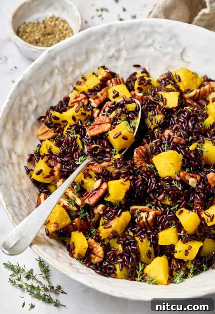 Black Rice Recipe in a white bowl with a spoon, garnished with butternut squash.