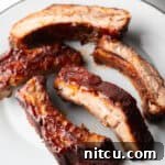 A white plate with five air-fried baby back ribs, garnished and ready to eat.