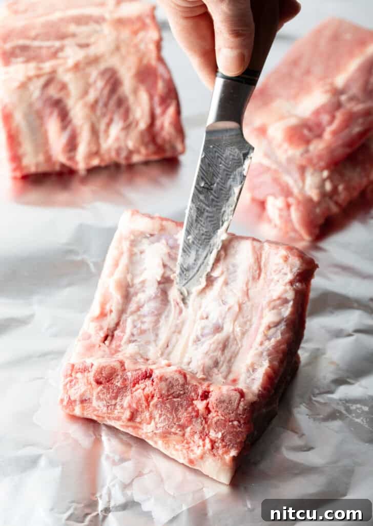 Cutting a rack of 4 baby back ribs into individual ribs.
