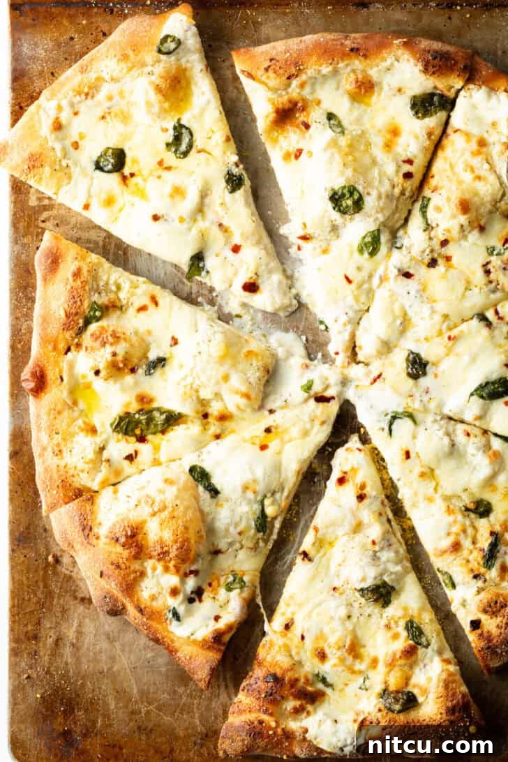 Top down view of a white pizza cut into 8 slices on a baking sheet.