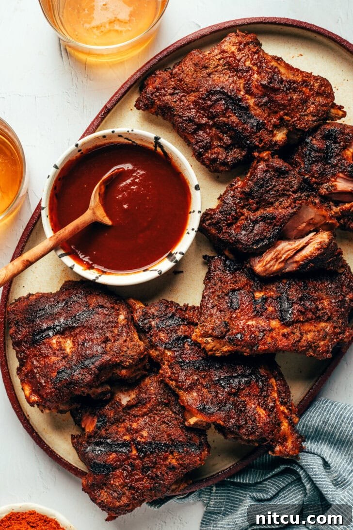 Perfectly cooked baby back ribs on a platter with homemade barbecue sauce