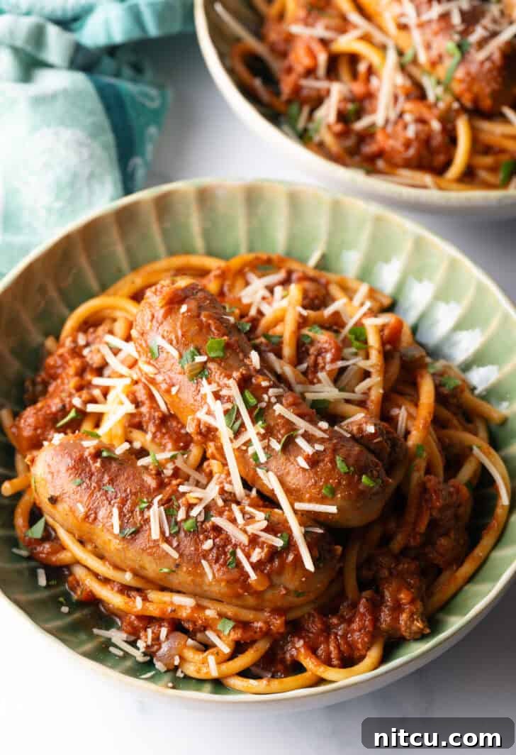 Green bowl with Sunday gravy pasta with meat sauce and sausages.