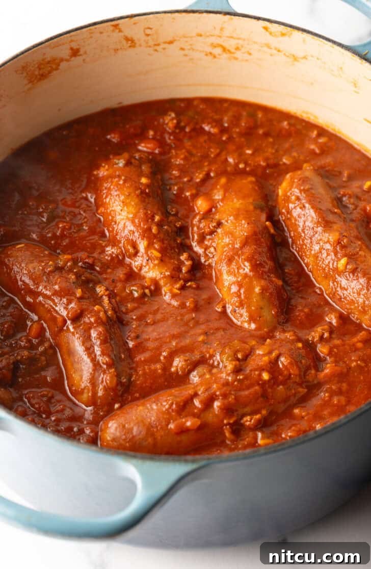 Large Italian sausages cooking in tomato sauce.