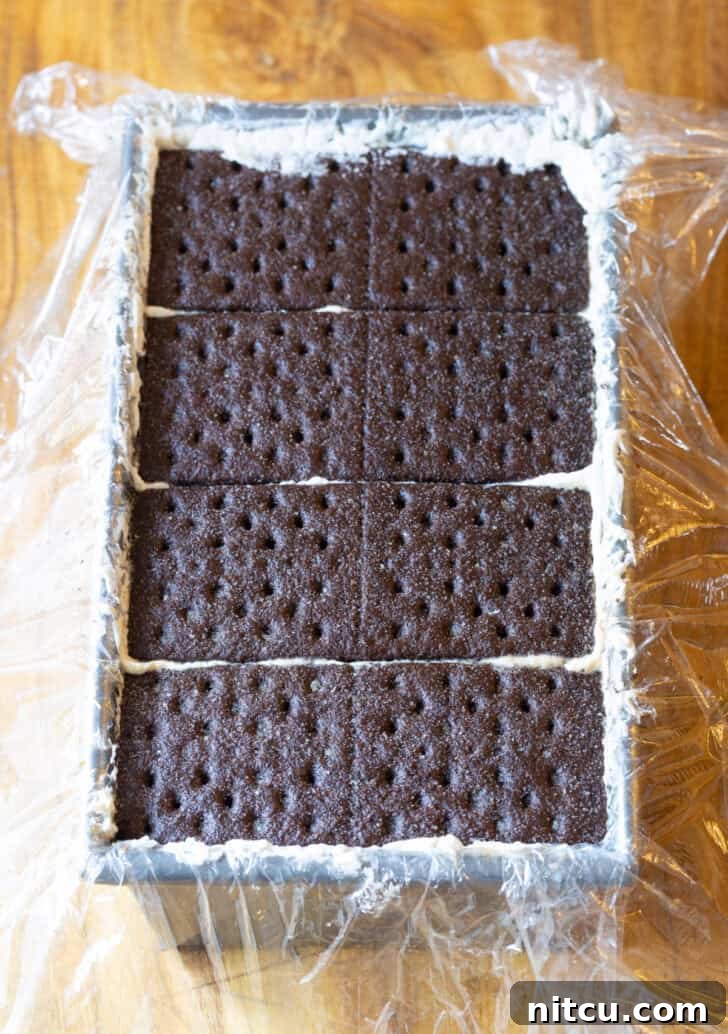 Layering chocolate graham crackers in a rectangle baking pan.