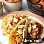Three chicken tacos with chopped avocado on a plate together.