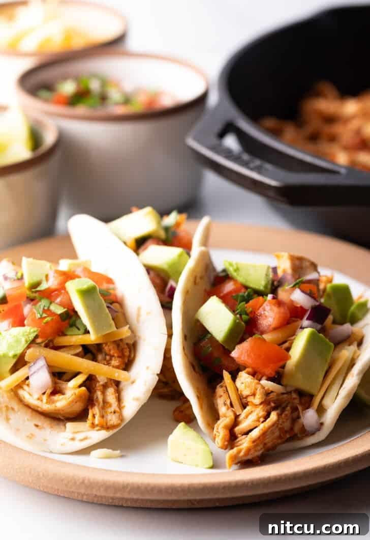 Three chicken tacos with chopped avocado on a plate together, highlighting the simple yet appealing presentation.