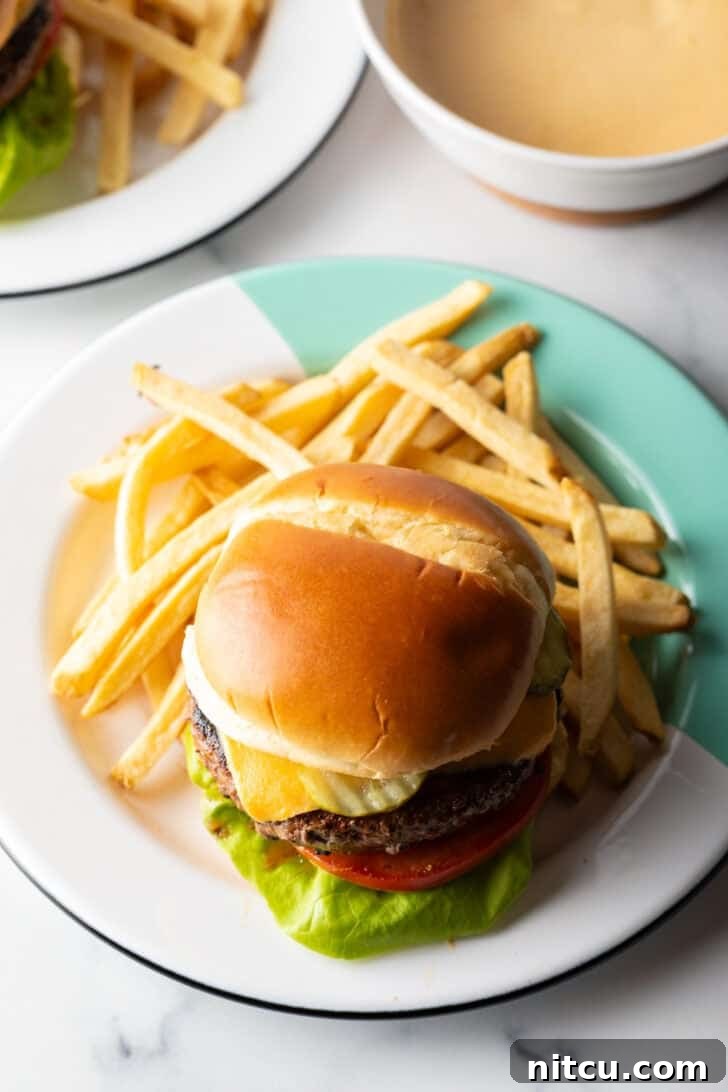 A perfectly cooked burger on a plate, surrounded by a pile of golden french fries, ready to be enjoyed.