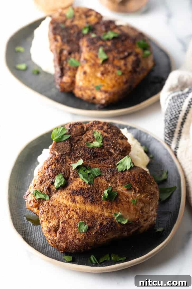Browned seasoned bone-in pork chop on a plate, garnished with chopped parsley, showcasing its crispy exterior.