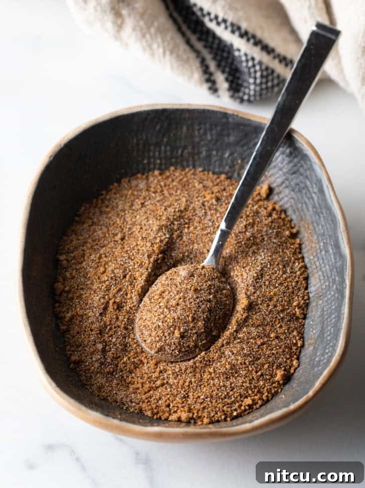 Blend of spices being mixed in an oval dish with a metal spoon.