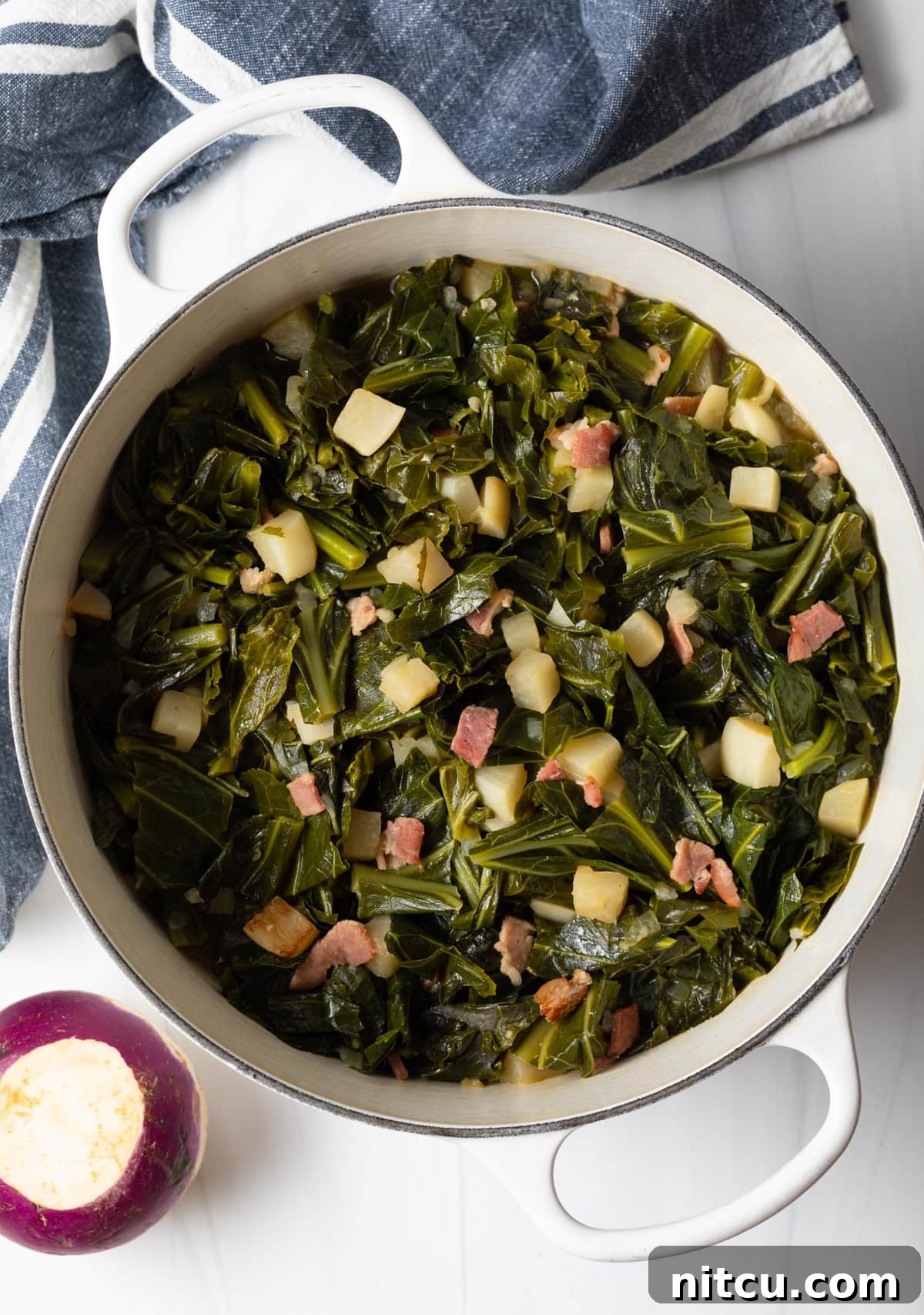 Overhead shot of perfectly seasoned spicy collard greens simmering in a Dutch oven, ready to serve.
