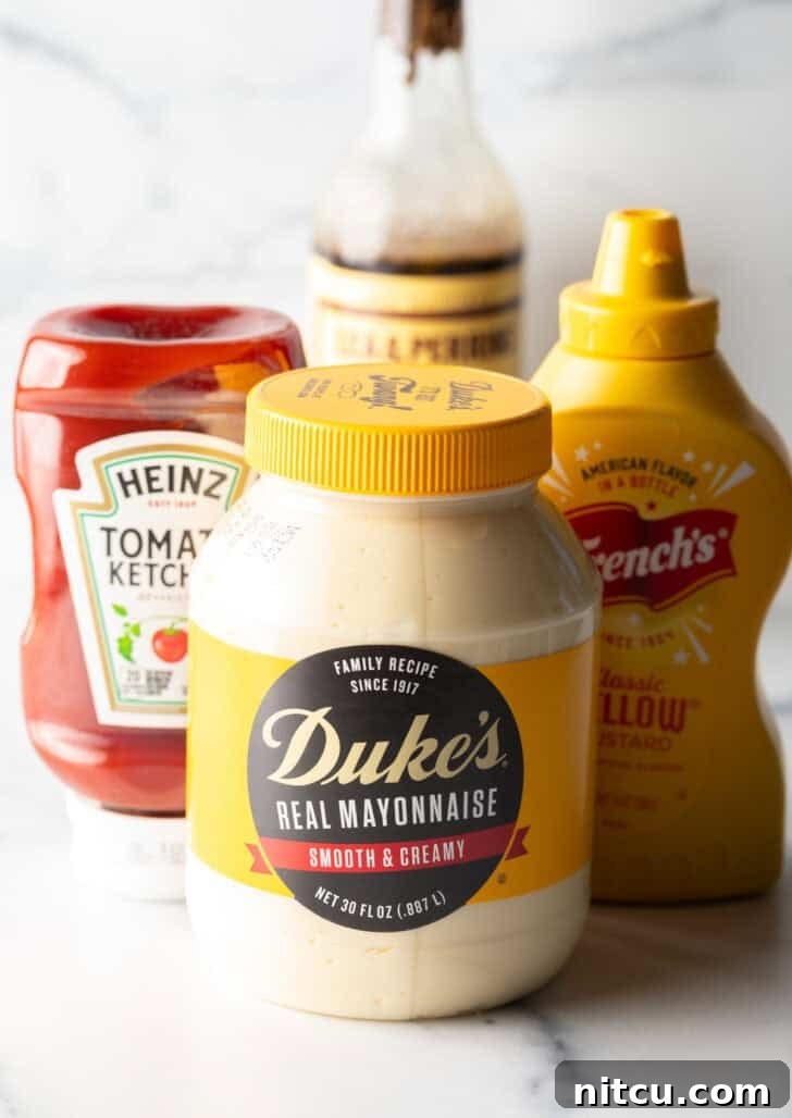 Individual bottles and jar of the four core ingredients: mayonnaise, yellow mustard, ketchup, and Worcestershire sauce, neatly arranged on a surface.