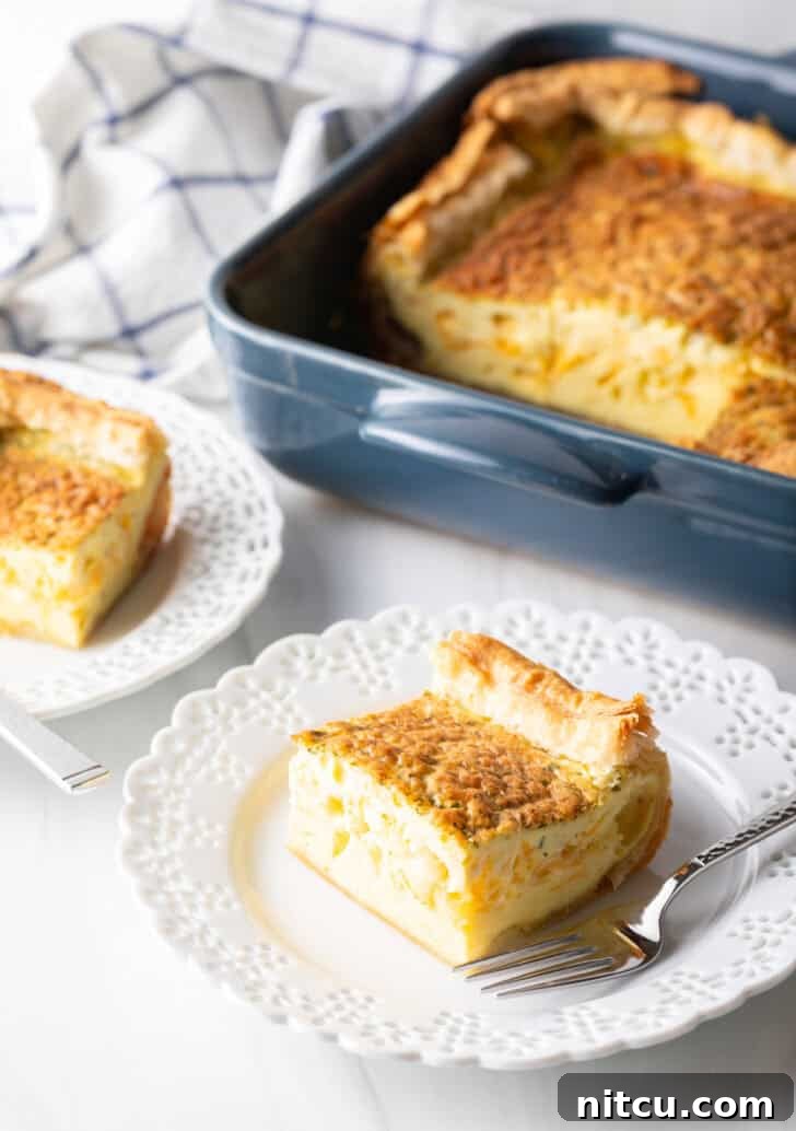 A delightful square of egg casserole sits proudly on a white plate with a fork, while the baking dish with the remaining casserole waits patiently in the soft-focus background.