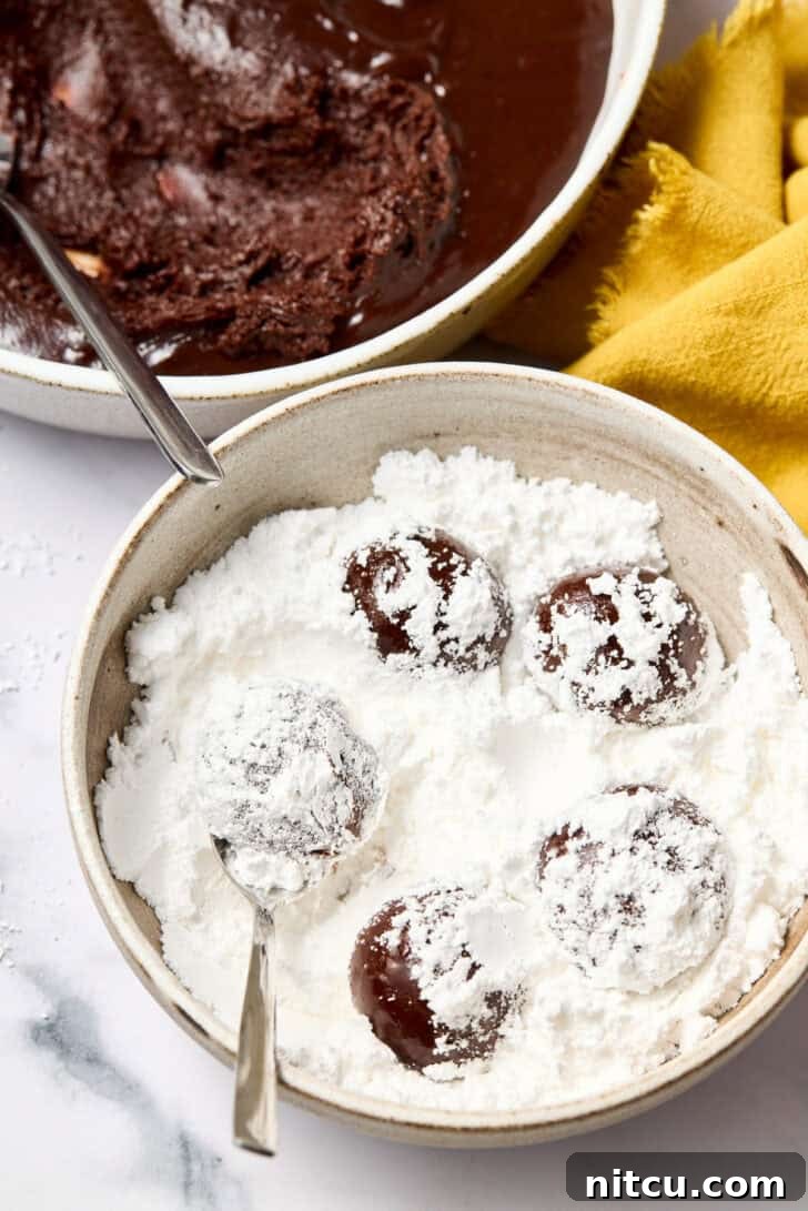 Mexican Crinkle Cookies dough balls rolled generously in powdered sugar, ready for baking.