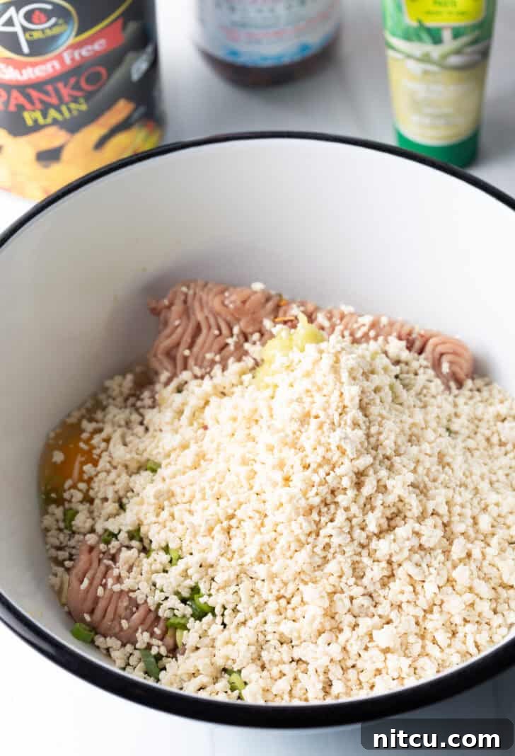 Ground turkey in a white bowl, covered in panko breadcrumbs, before mixing.