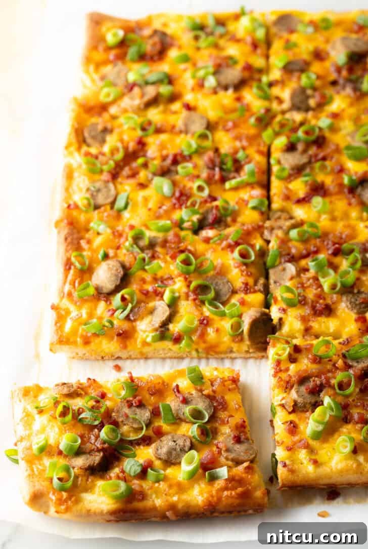 A rectangular baking sheet tray showcasing a vibrant breakfast pizza, generously loaded with melted cheese, sliced sausage, and fresh green onions. The pizza has been perfectly cut into 8 individual rectangular slices, with one piece gently pulled away, highlighting its inviting layers.
