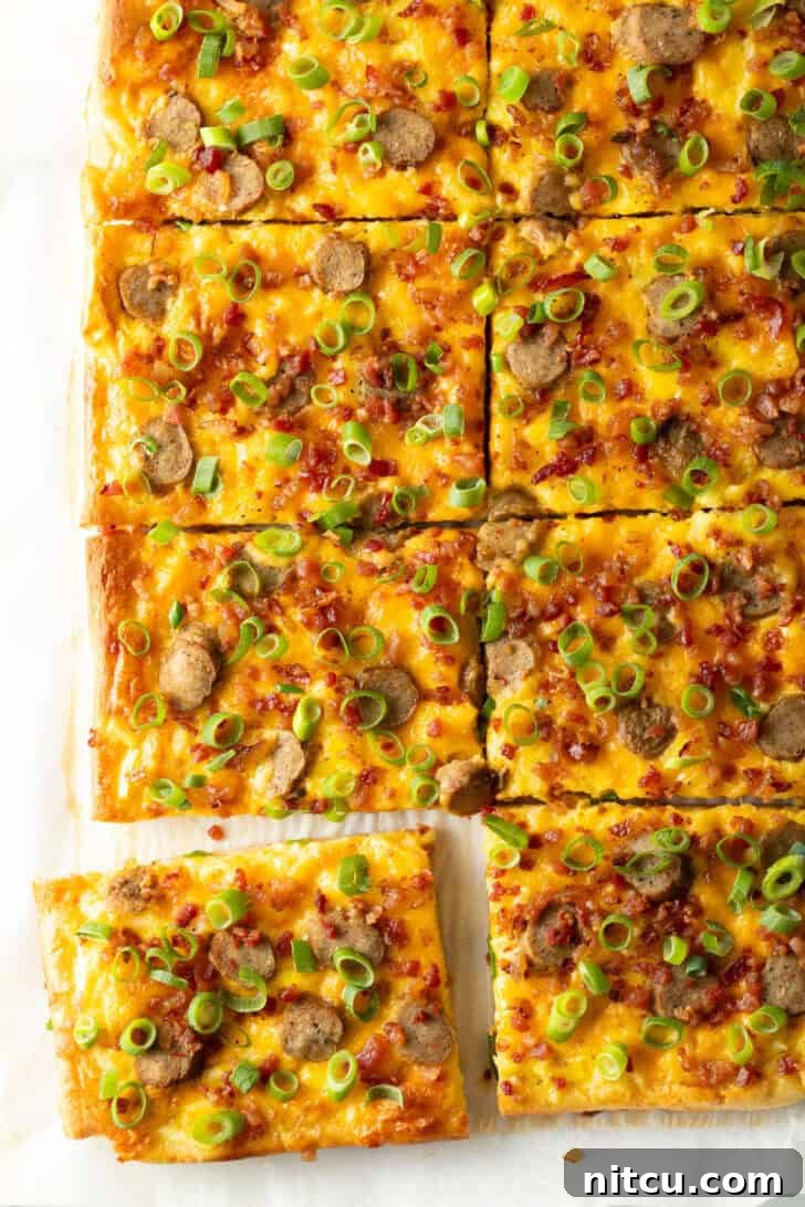 Another perspective of the rectangular baking sheet tray featuring the finished breakfast pizza, richly adorned with melted cheese, savory sausage, and fresh green onions. The pizza has been meticulously cut into 8 rectangular portions, with one slice slightly separated to highlight its perfect crust and enticing toppings.