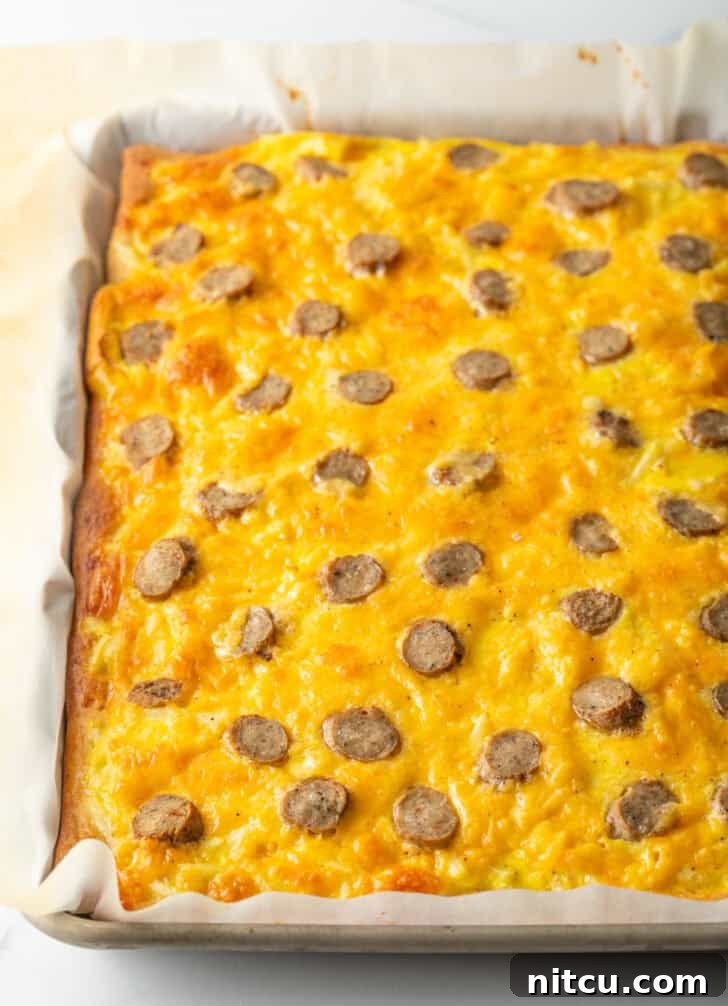 A fully baked rectangular pizza, glistening with melted cheeses and topped with perfectly cooked sausage slices, fresh out of the oven.